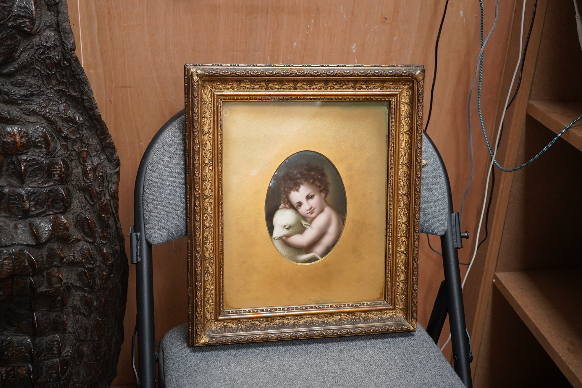 A German oval porcelain plaque with putto and lamb, possibly KPM, ornately gilt framed, overall 39 x 33cm. Condition - fair